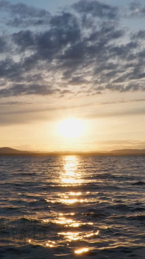 A beautiful sunset on the lake with the reflection of the sun in the calm waves. Stock Footage 267647343