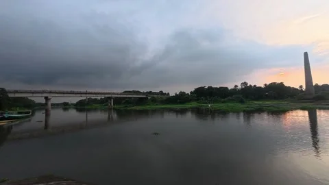 Beautiful sunset over calm river with brick kiln chimney in distance Stock Footage 342157151