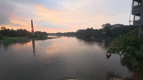 Beautiful sunset over calm river with brick kiln chimney in distance Stock Footage 342158881