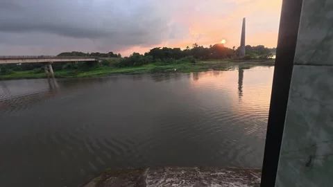Beautiful sunset over calm river with brick kiln chimney in distance Stock Footage 342158959