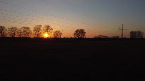 A beautiful sunset over a field with power lines in the background Stock Footage 296098904