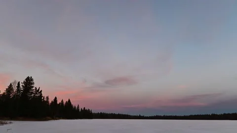 Beautiful sunset over a lake lined with silhouettes of spruce and pine trees.  Stock Footage 143667541