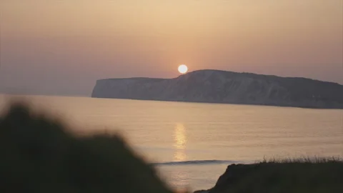 A beautiful sunset over the ocean with a large rock in the background Stock Footage 298258919