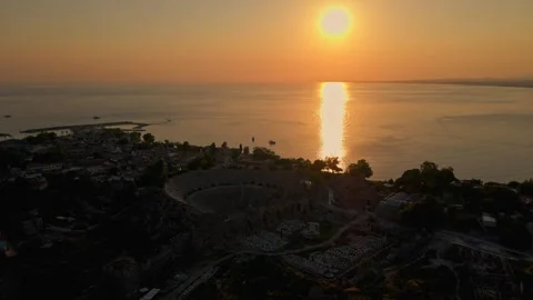 A beautiful sunset over the ocean with a large amphitheater in the background Stock Footage 327924124