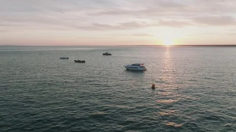 A beautiful sunset over the ocean with several boats floating on the water Stock Footage 297949769