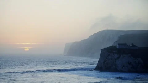 A beautiful sunset over the ocean with a small house in the distance Stock Footage 303987176