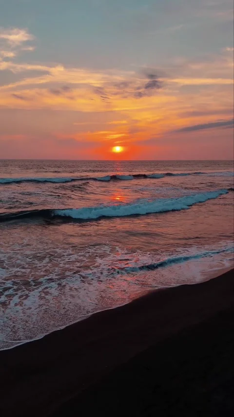 Beautiful Sunset Over the Ocean with Waves Crashing on Dark Sand Beach 스톡 동영상 332039858