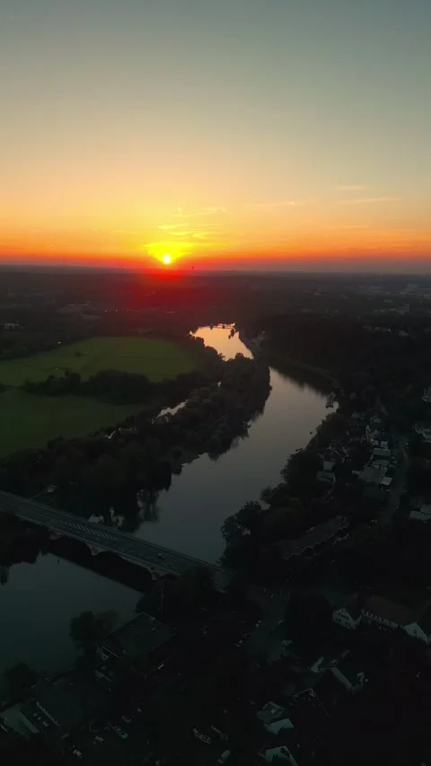 Beautiful sunset over the river running on the city's edge through green fields Stock Footage 250524782