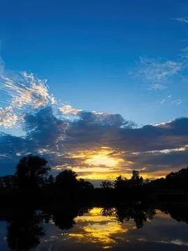 Beautiful sunset over river with trees and reflection Stock Photos