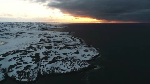 A beautiful sunset over the shore of the Arctic Ocean covered with snow, a storm Stock Footage 169463755