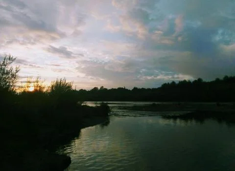 Beautiful Sunset Over Tranquil River Surrounded by Forests and Hills Stock Photos