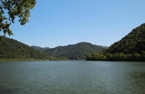 Beautiful Sunset Over Tranquil River Surrounded by Forests and Hills Stock Photos