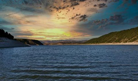 Beautiful Sunset Over Tranquil River Surrounded by Forests and Hills Stock Photos