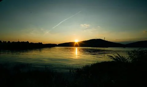 Beautiful Sunset Over Tranquil River Surrounded by Forests and Hills Stock Photos