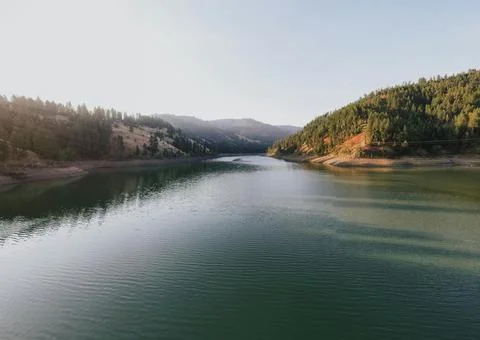 Beautiful Sunset Over Tranquil River Surrounded by Forests and Hills Stock Photos