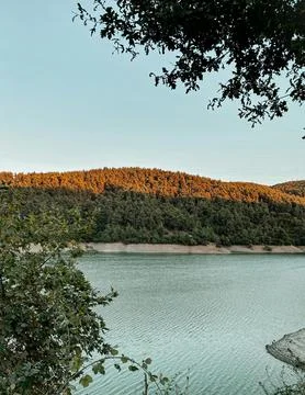 Beautiful Sunset Over Tranquil River Surrounded by Forests and Hills Stock Photos