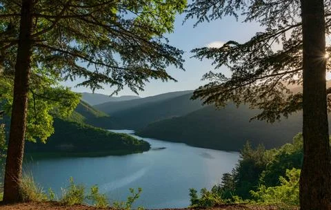 Beautiful Sunset Over Tranquil River Surrounded by Forests and Hills Stock Photos