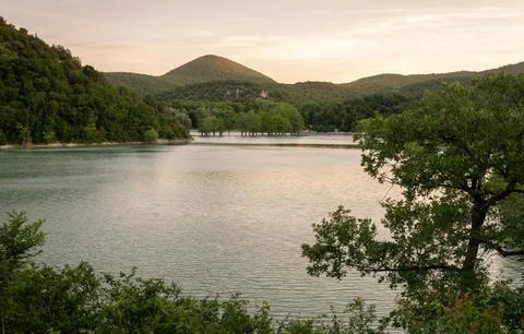 Beautiful Sunset Over Tranquil River Surrounded by Forests and Hills Stock Photos