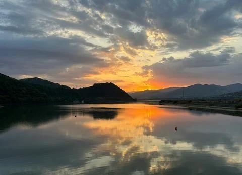 Beautiful Sunset Over Tranquil River Surrounded by Forests and Hills Stock Photos