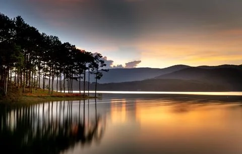 Beautiful Sunset Over Tranquil River Surrounded by Forests and Hills Stock Photos