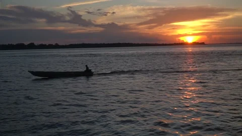 Beautiful sunset on the Rio Amazonas River. Man sailing on boat at amazon dusk. Stock Footage 150891599