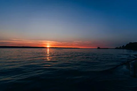 Beautiful sunset on river with outgoing red sun and blue sky Stock Photos