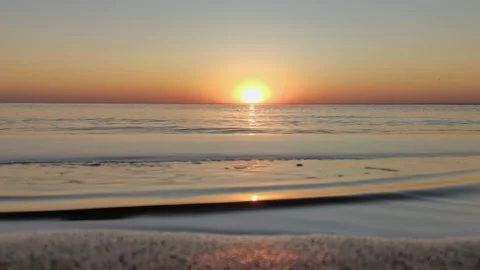 Beautiful sunset on sandy beach over a quiet calm sea. Video stock 165746565