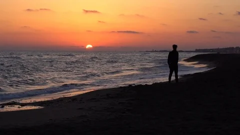 Beautiful sunset on the sea, young man walking on the beach. Epic cloudy sky, sa Stock Footage 80469830