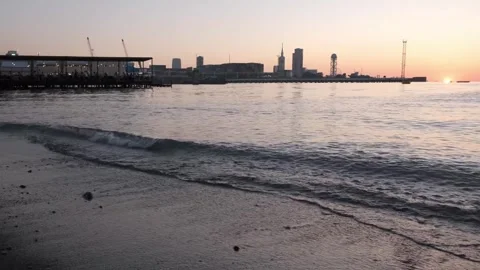 Beautiful sunset on the seashore against the backdrop of a modern city. Stock Footage 248971878