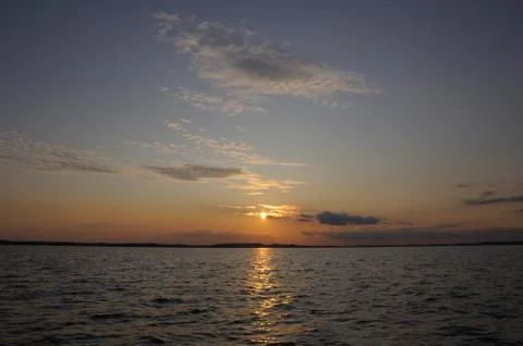 Beautiful sunset through small clouds over lake Stock Photos