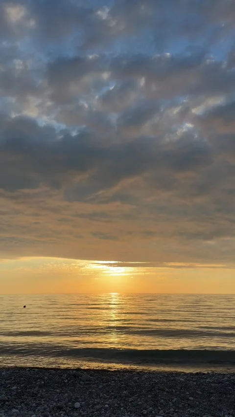Beautiful sunset under dramatic cloudy sky over the calm Black Sea in Georgia Видео 337614415