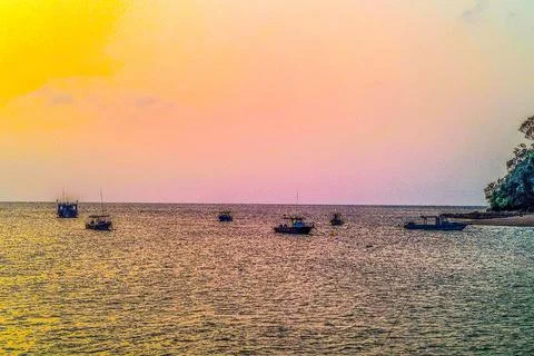 A beautiful sunset view by the beach while watching the boats on the water Stock Photos