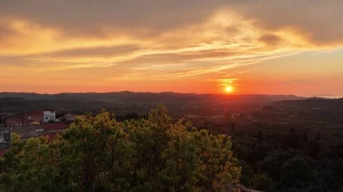 Beautiful sunset view behind green tree branches looking over the hills of Stock Footage 339036593