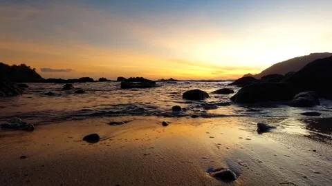 A beautiful sunset view with crashing waves on a rocky beach. Stock Footage 303258495