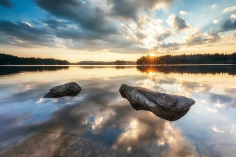 Beautiful sunset view with sun rays over a mountain lake 스톡 사진