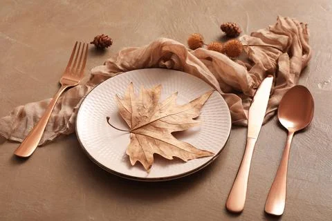 Beautiful table setting with autumn leaf and pine cones on brown background,  Stock Photos