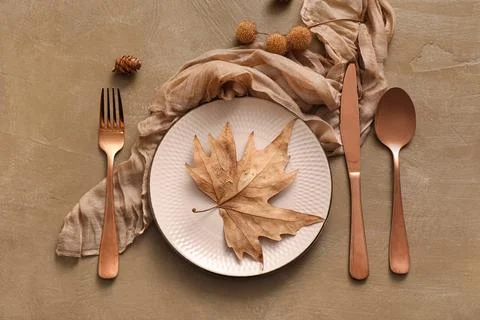 Beautiful table setting with autumn leaf and pine cone on brown background Stock Photos