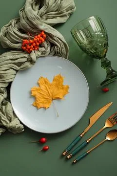 Beautiful table setting with autumn leaf and berries on green background Stock Photos