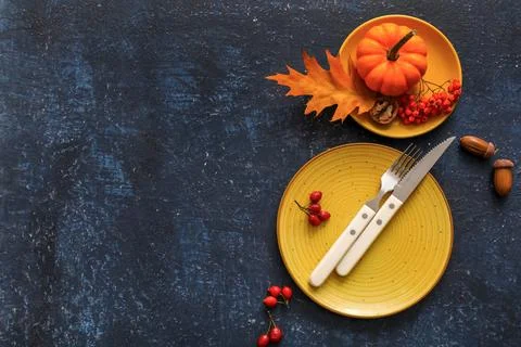 Beautiful table setting with berries, pumpkin, acorns and autumn leaf on blue Stock Photos