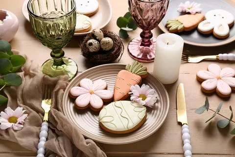 Beautiful table setting with different Easter cookies, eggs, burning candle a Stock Photos