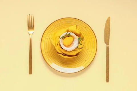 Beautiful table setting with Easter egg and leaves on yellow background Stock Photos
