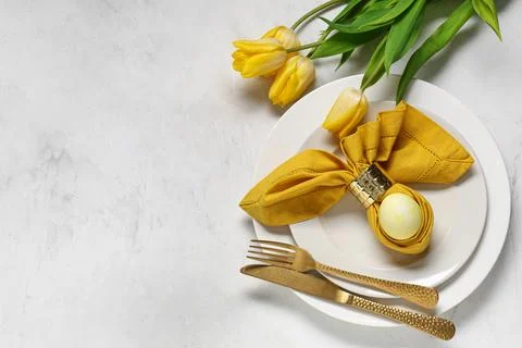 Beautiful table setting with Easter egg and yellow tulip flowers on white bac Stock Photos