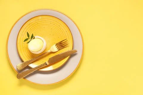 Beautiful table setting with Easter egg and leaves on yellow background Stock Photos