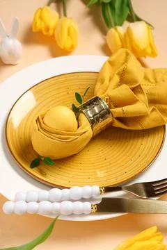 Beautiful table setting with Easter egg and yellow tulip flowers on beige bac Stock Photos