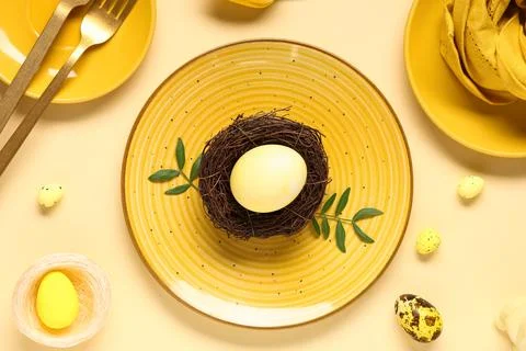 Beautiful table setting with Easter eggs and leaves on yellow background Stock Photos