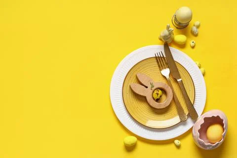 Beautiful table setting with Easter eggs and toy bunny on yellow background Stock Photos