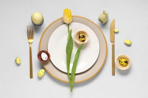 Beautiful table setting with Easter eggs, toy bunny and yellow tulip flower o Stock Photos