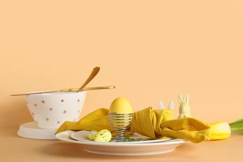Beautiful table setting with folded napkin and Easter eggs on beige table Stock Photos