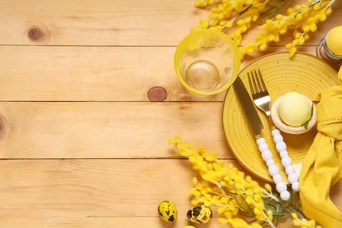 Beautiful table setting with folded napkin, painted eggs and yellow flowers o Stock Photos