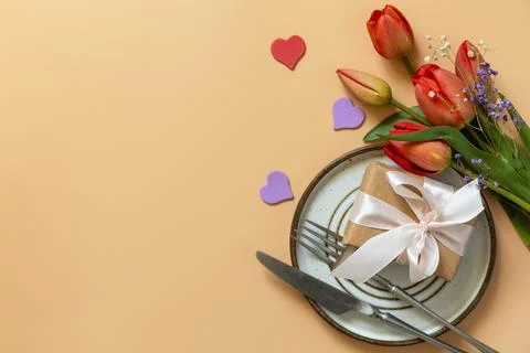 Beautiful table setting with  gift box, decorative hearts and tulips flower.. Stock Photos